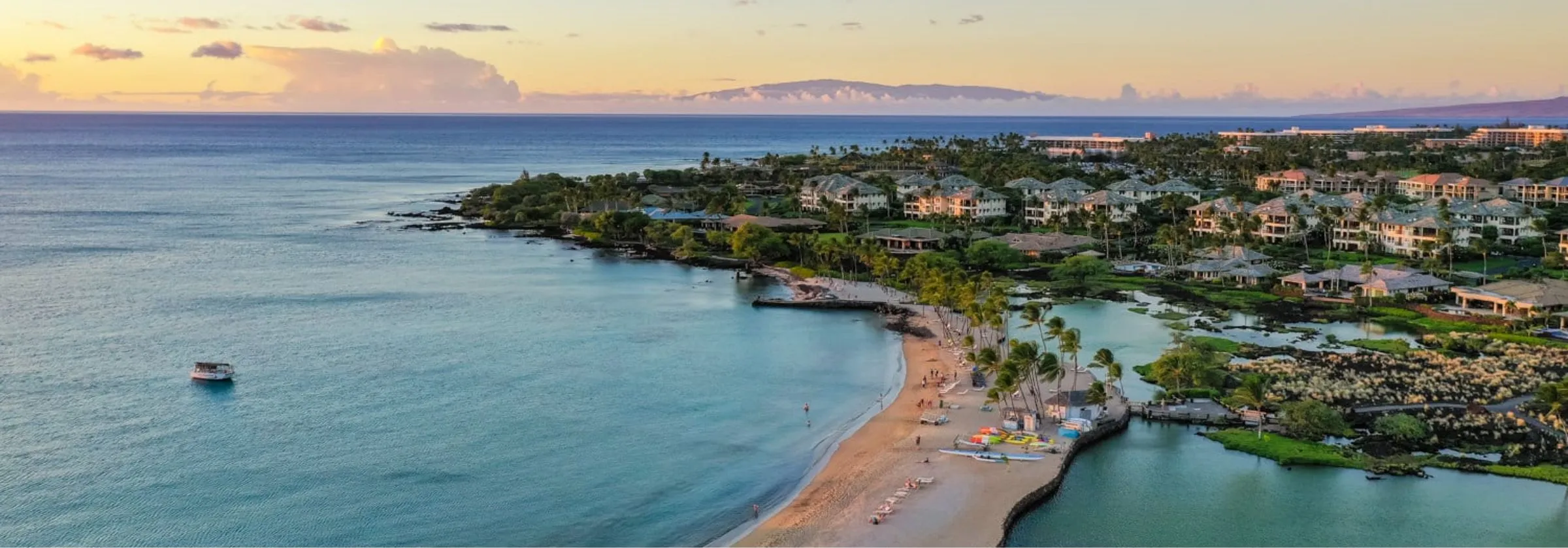 Aerial view of a beach with calm ocean and distant mountains.