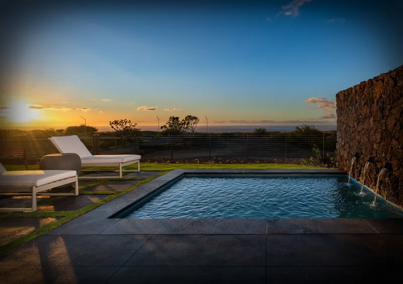Person walking through grassy field with mountains in the background.