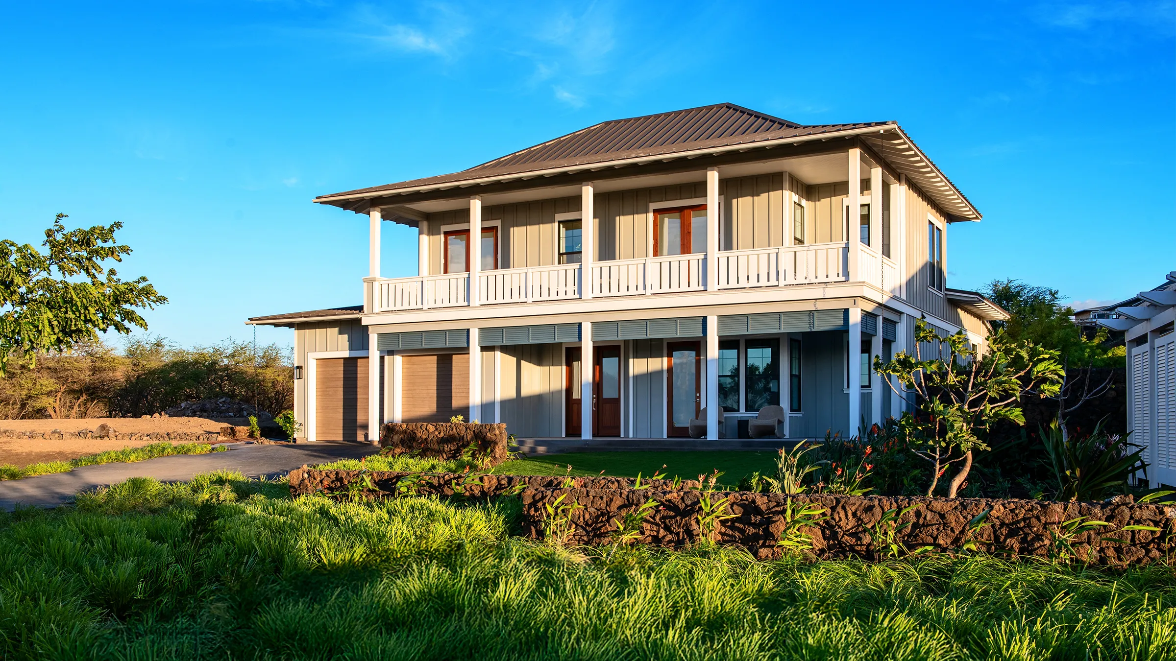 Two-story white house with a garage, surrounded by greenery.
