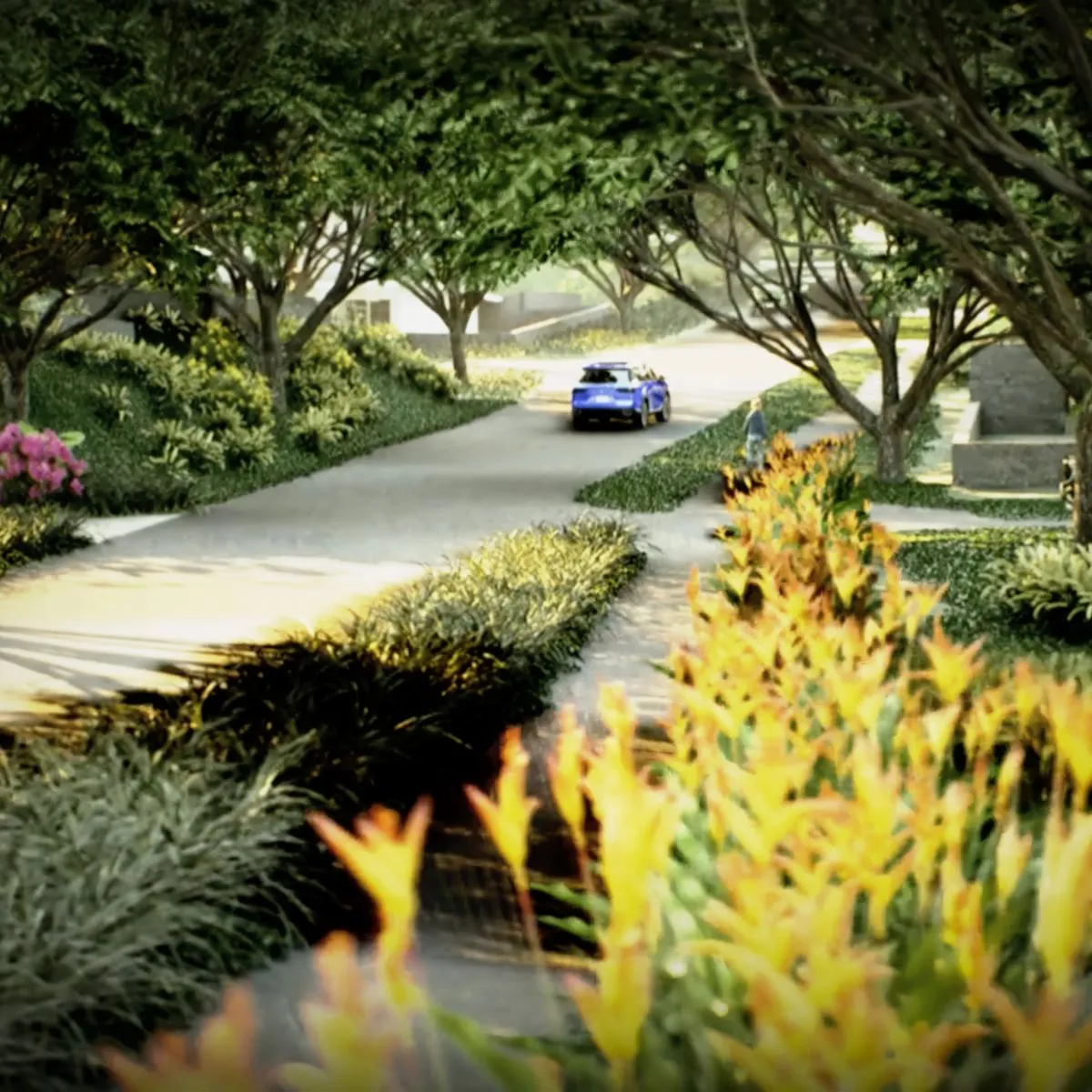 A blue car drives down a tree-lined road with vibrant flowers.