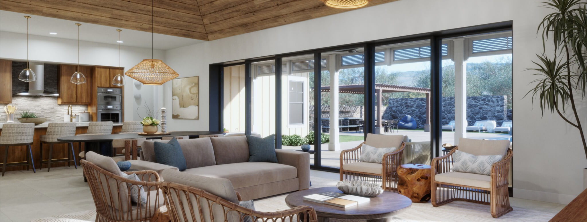 Modern living room by Nana Kai Homes featuring wicker chairs, a beige sofa, wooden accents, and large windows. The kitchen area is visible with stylish stools and pendant lights. Outdoor views showcase a charming stone wall surrounded by lush greenery.