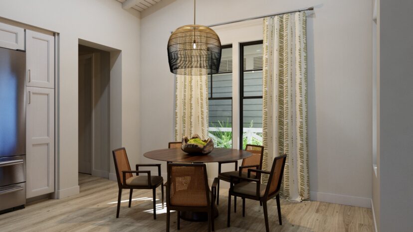 A dining room with a round wooden table, four chairs, a fruit bowl centerpiece, and a modern pendant light. White walls and patterned curtains frame a large window.