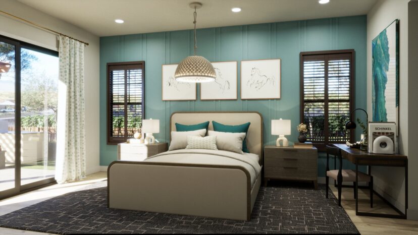 A modern bedroom with a large bed, teal accent wall, and framed art. Wooden shutters cover windows. A desk with a lamp and decor is on the right. Sliding glass doors lead outside.