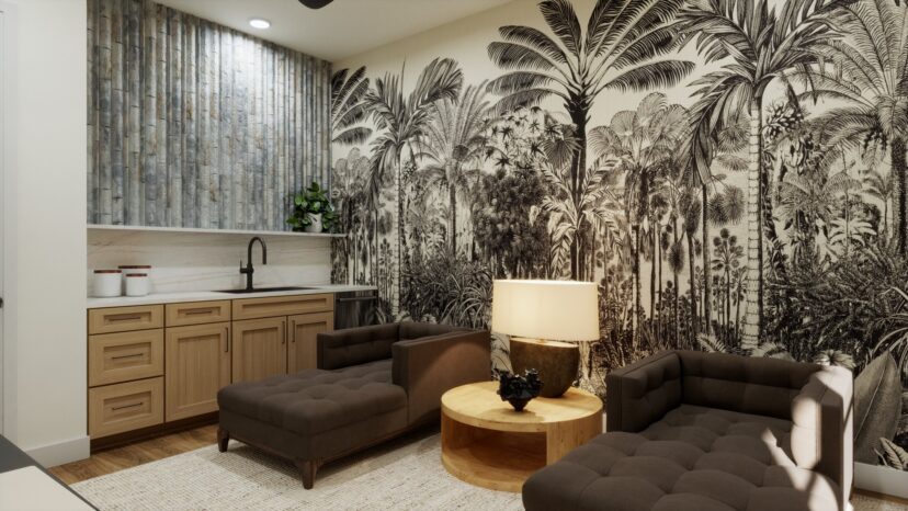 A modern lounge with two brown chairs, a round wooden table, a lamp, a kitchenette with a sink, and a decorative wall featuring a black and white tropical forest mural.